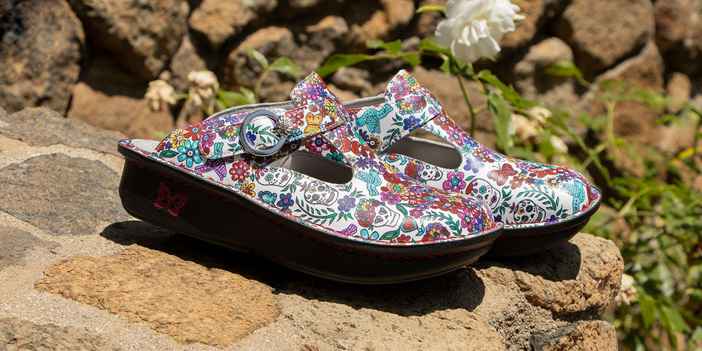 This Classic Clog fits like a dream with an adjustable side buckle for a personalized fit. Sitting on a classic rocker outsole, featured in an Ofrenda White colorway with multi color printed florals on a leather upper. ALG-6164