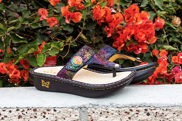 Featuring Carina Dynomite iridescent printed thong sandal with an artistic decorative button. 