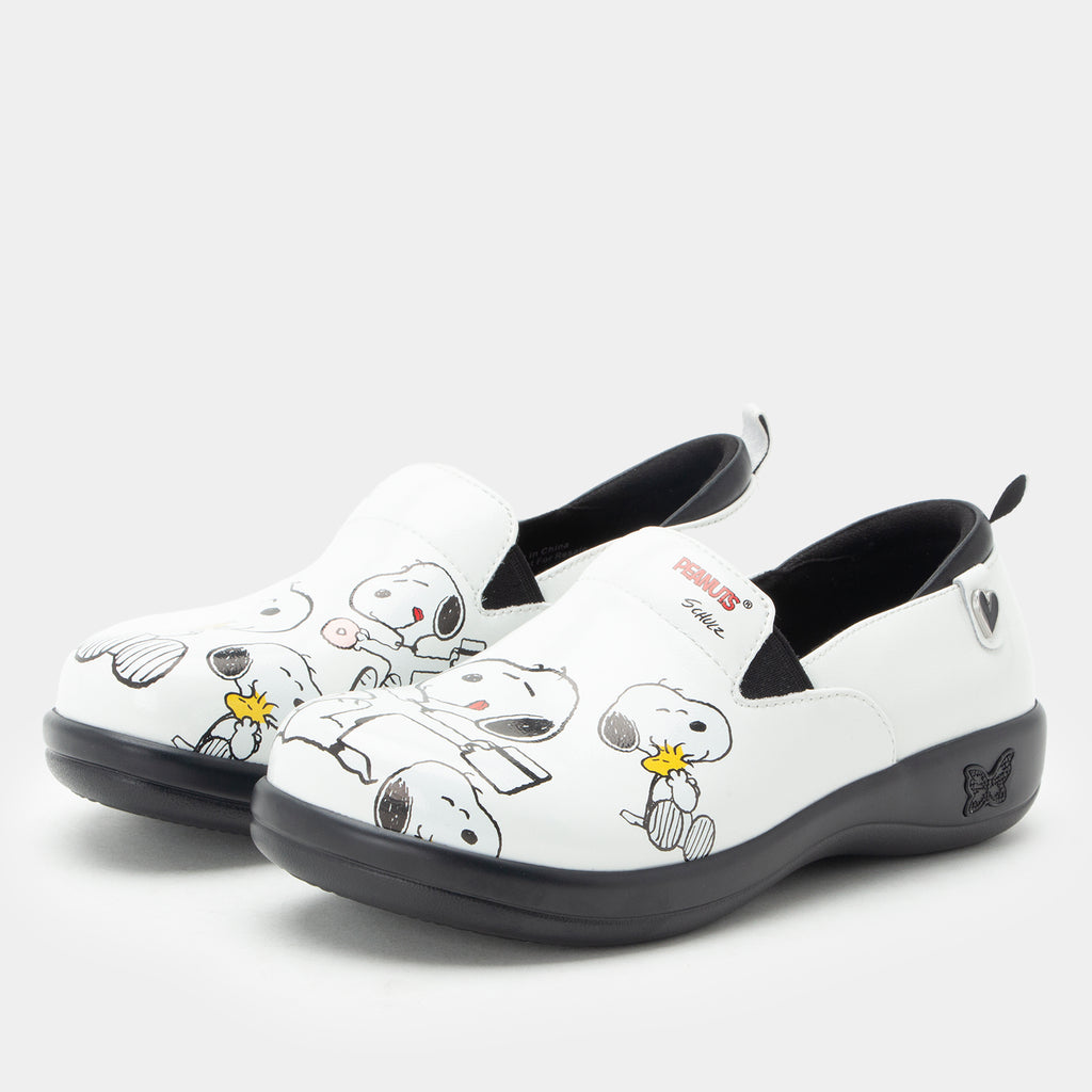 A pair of Alegria x Peanuts® white slip-on shoes featuring a black sole and cartoon Peanuts® characters print on the leather uppers. KEL-SNP19