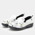 A pair of Alegria x Peanuts® white slip-on shoes featuring a black sole and cartoon Peanuts® characters print on the leather uppers. KEL-SNP19
